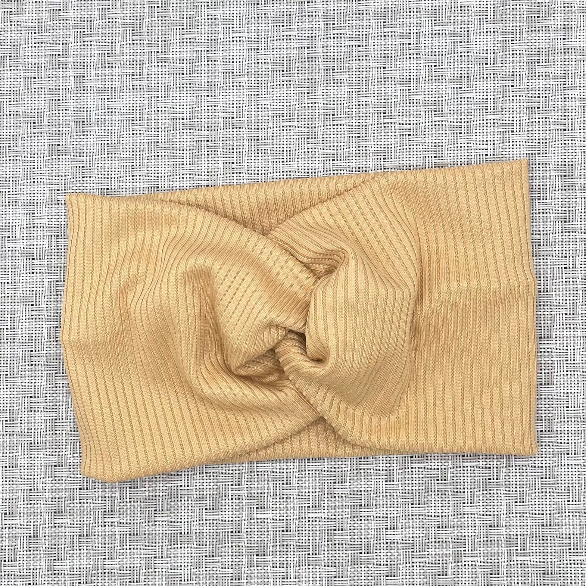 Wide, twisted headband with tan ribbed fabric.