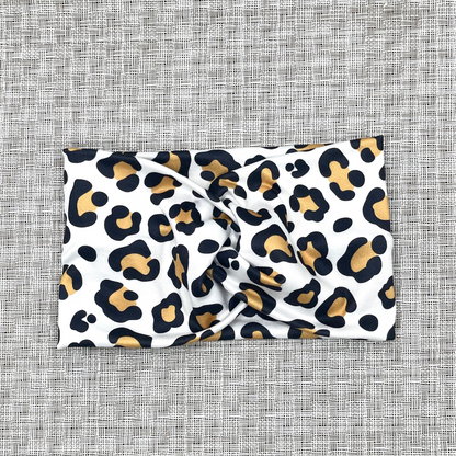 Wide, twisted headband in white with tan and black cheetah print.