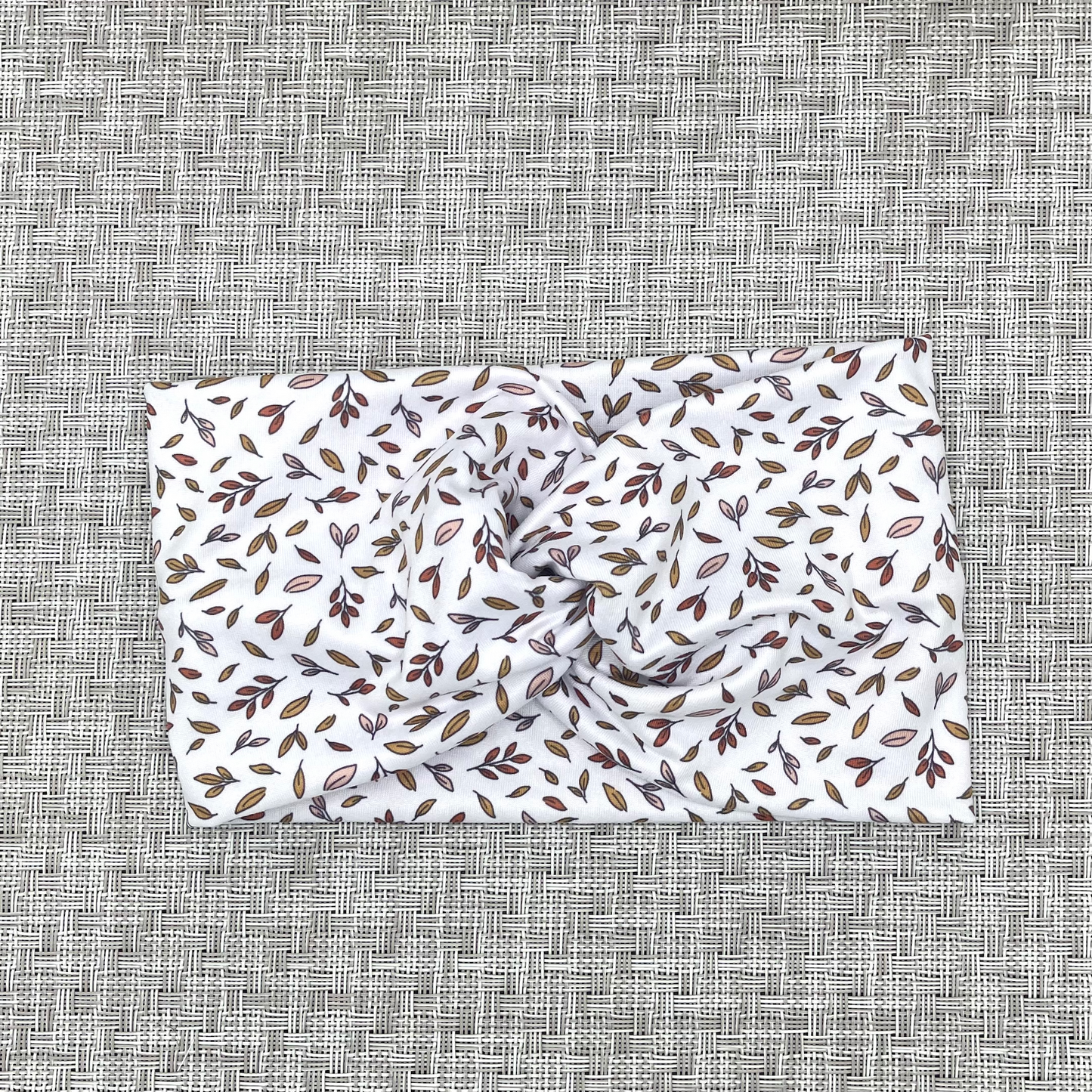 White, wide, twisted headband with brown/orange small leaves print.