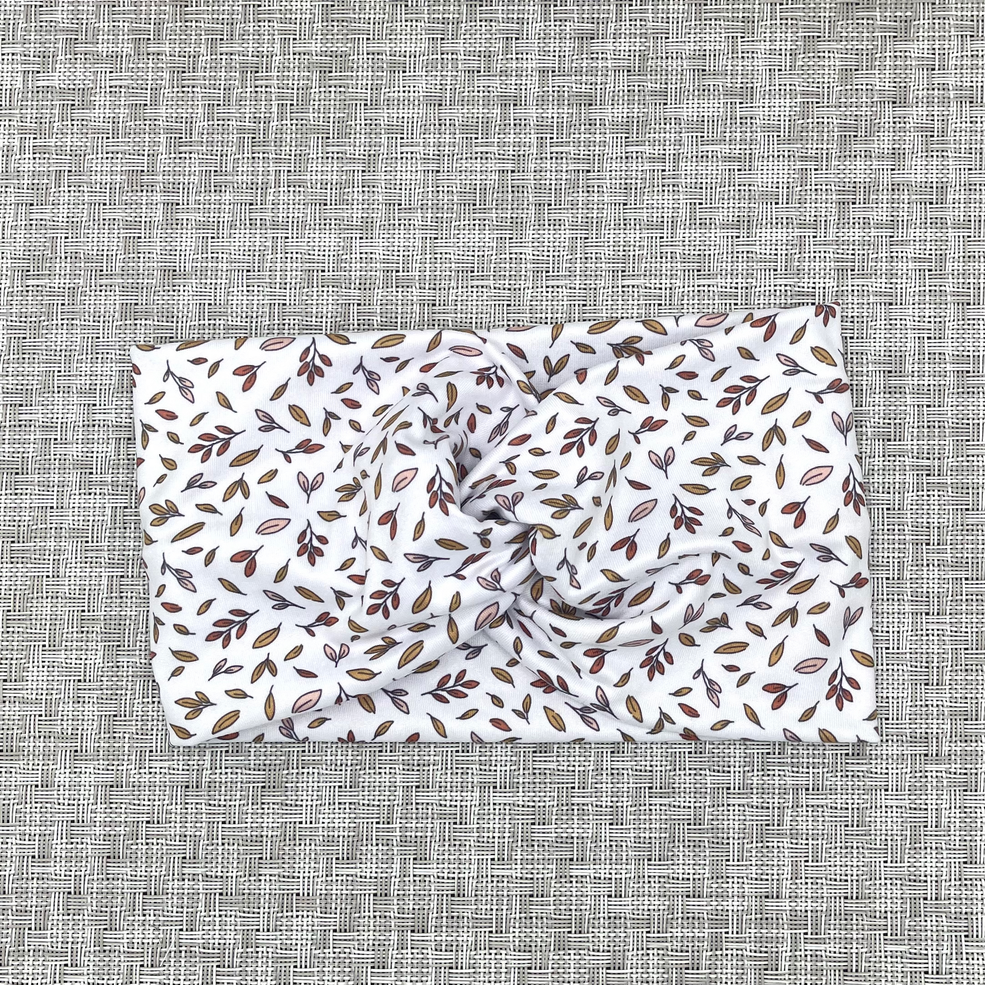 White, wide, twisted headband with brown/orange small leaves print.