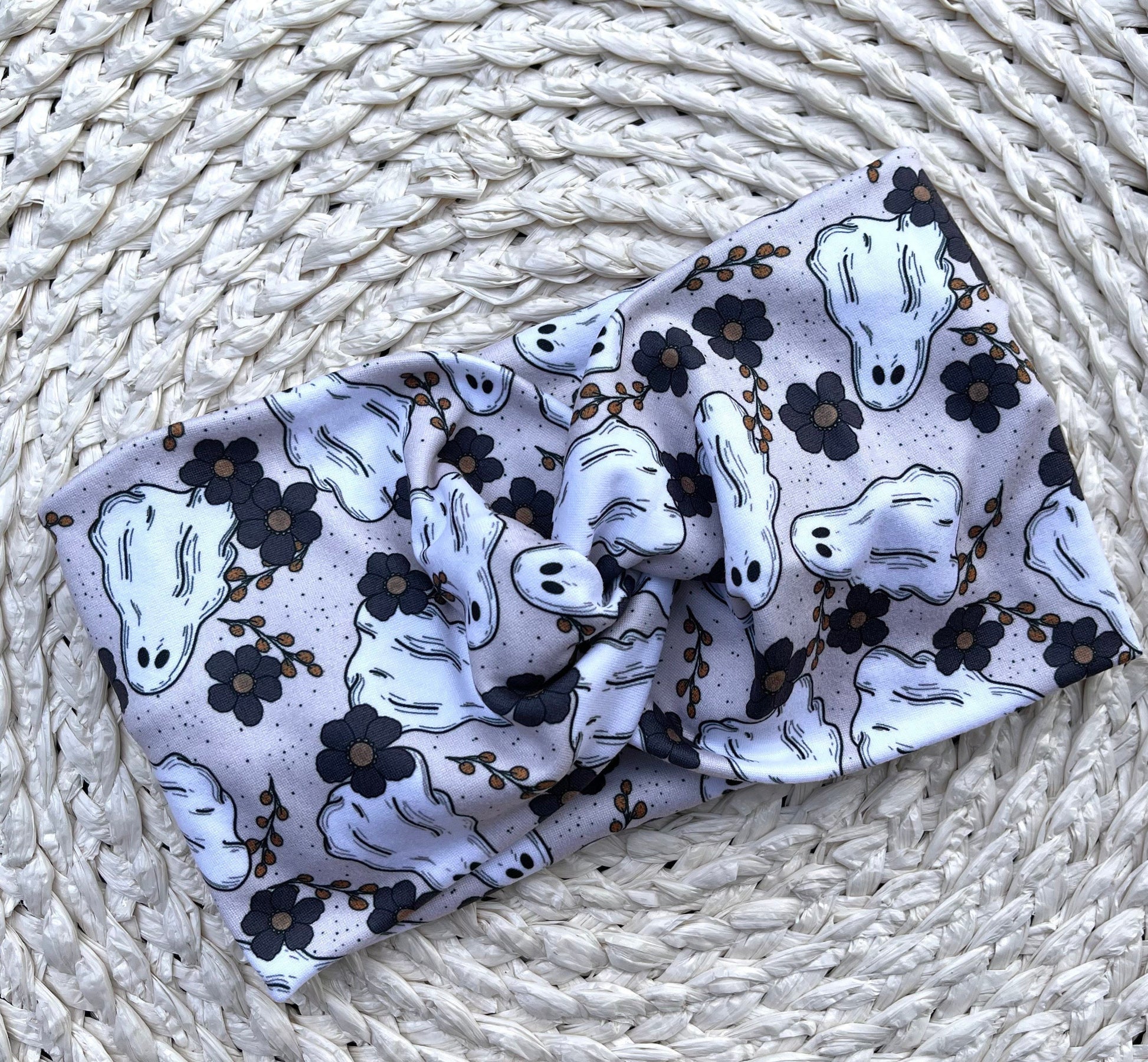 Wide, twisted headband in cream/gray with floral and ghost print.