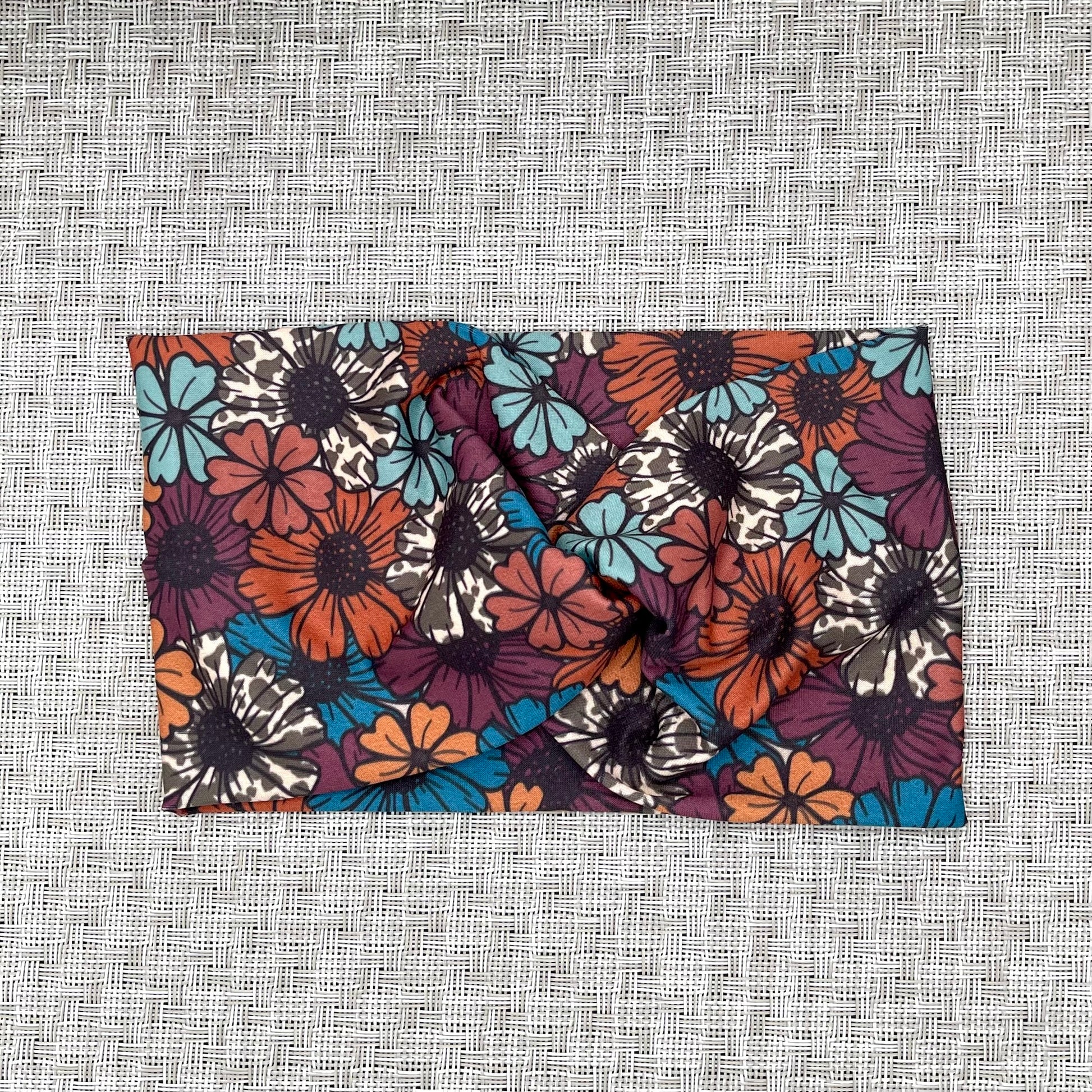 Wide, twisted headband in floral print with a navy/red color base with other colors within.