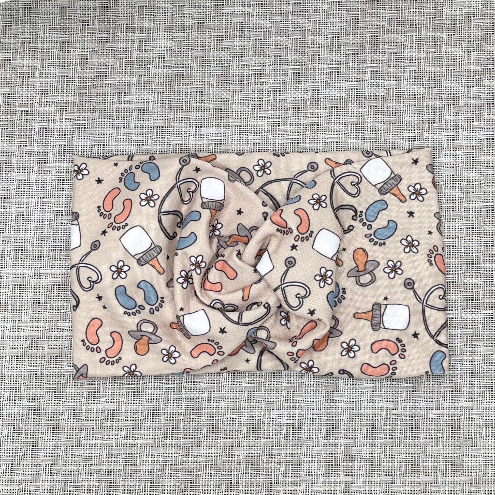 Baby-themed patterned headband on a textured gray background