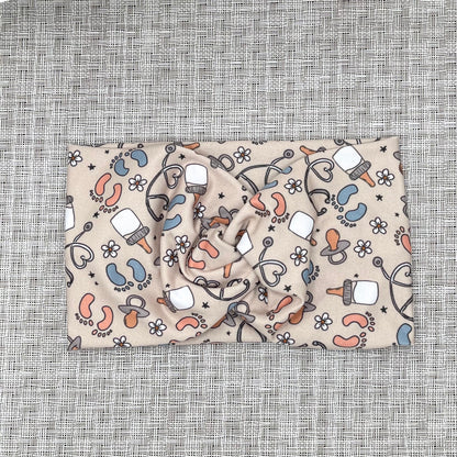 Baby-themed patterned headband on a textured gray background