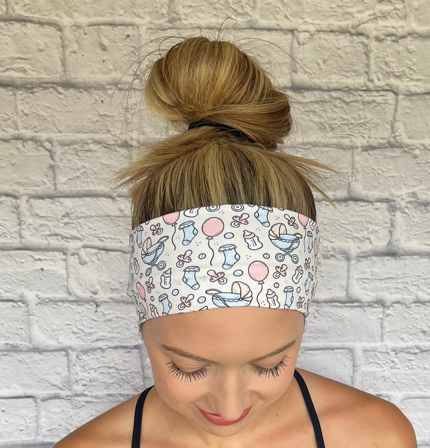 cream headband with baby theme print- baby bottles, socks, balloons, binkies, and buggy