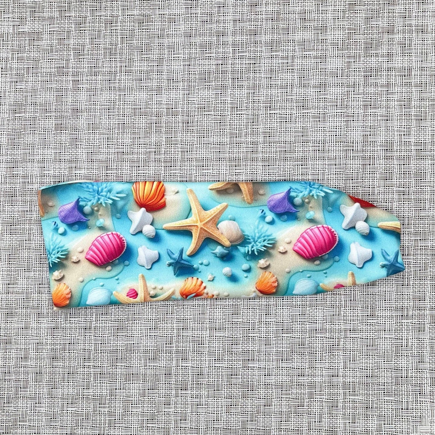 light blue headband with ocean theme print- water, sand, starfish, and shells