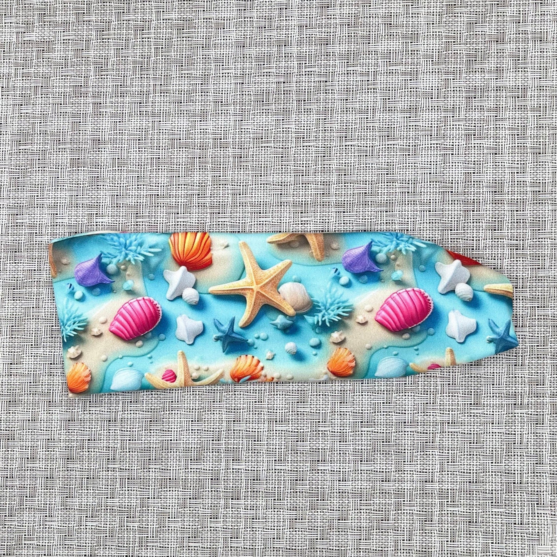 light blue headband with ocean theme print- water, sand, starfish, and shells