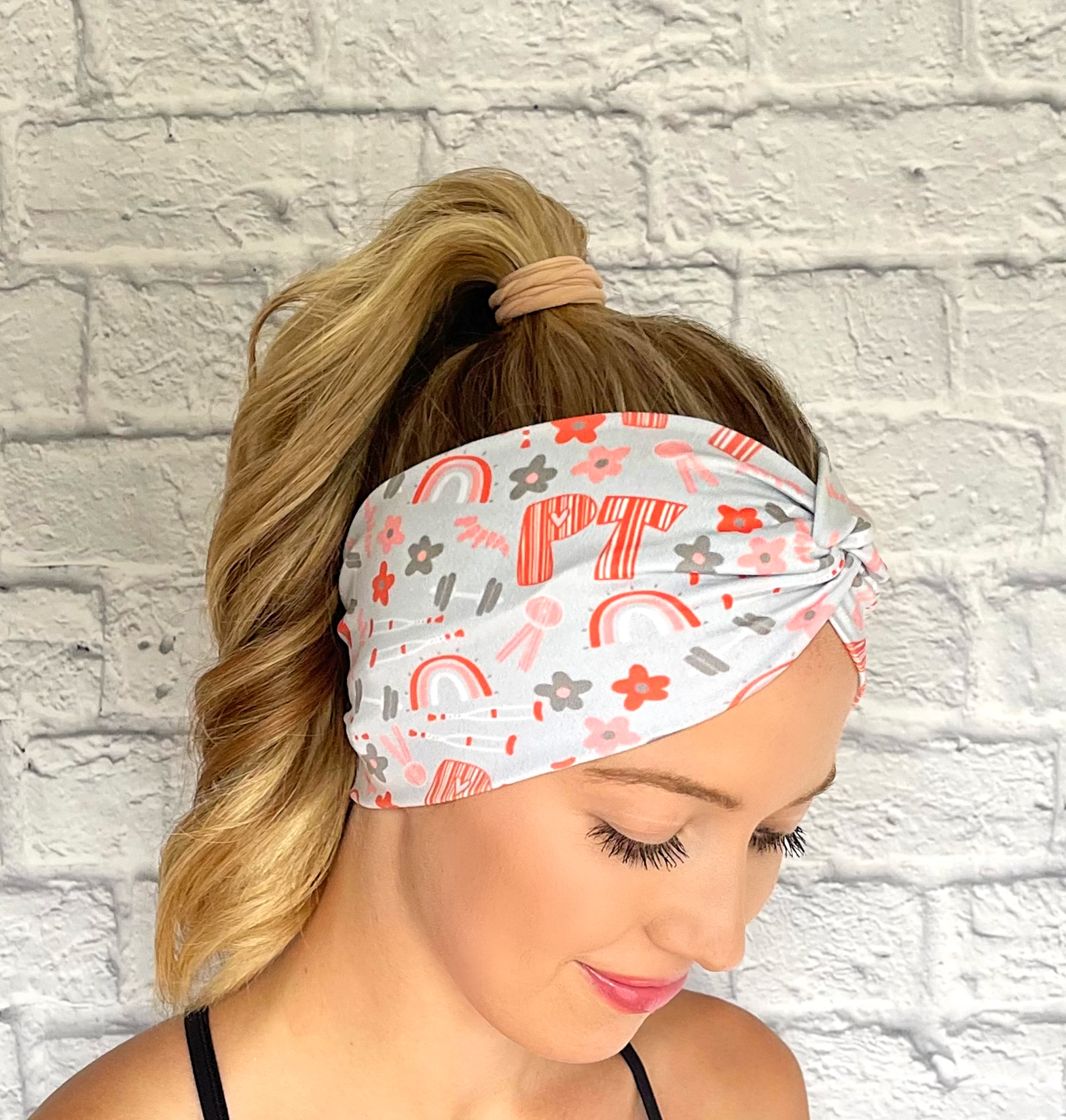 light blue/gray wide twist headband with "PT" print in orange and PT theme print with flowers in dark gray/blue and orange