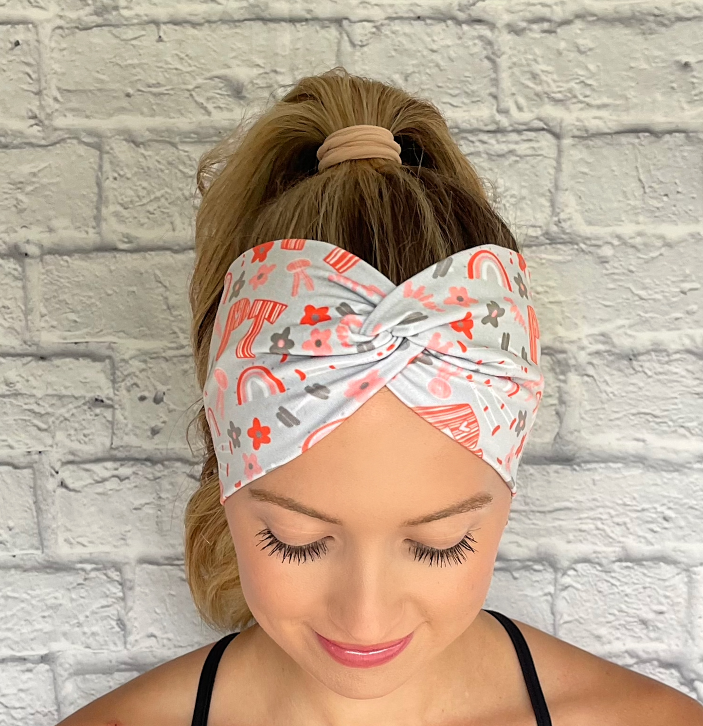 light blue/gray wide twist headband with "PT" print in orange and PT theme print with flowers in dark gray/blue and orange