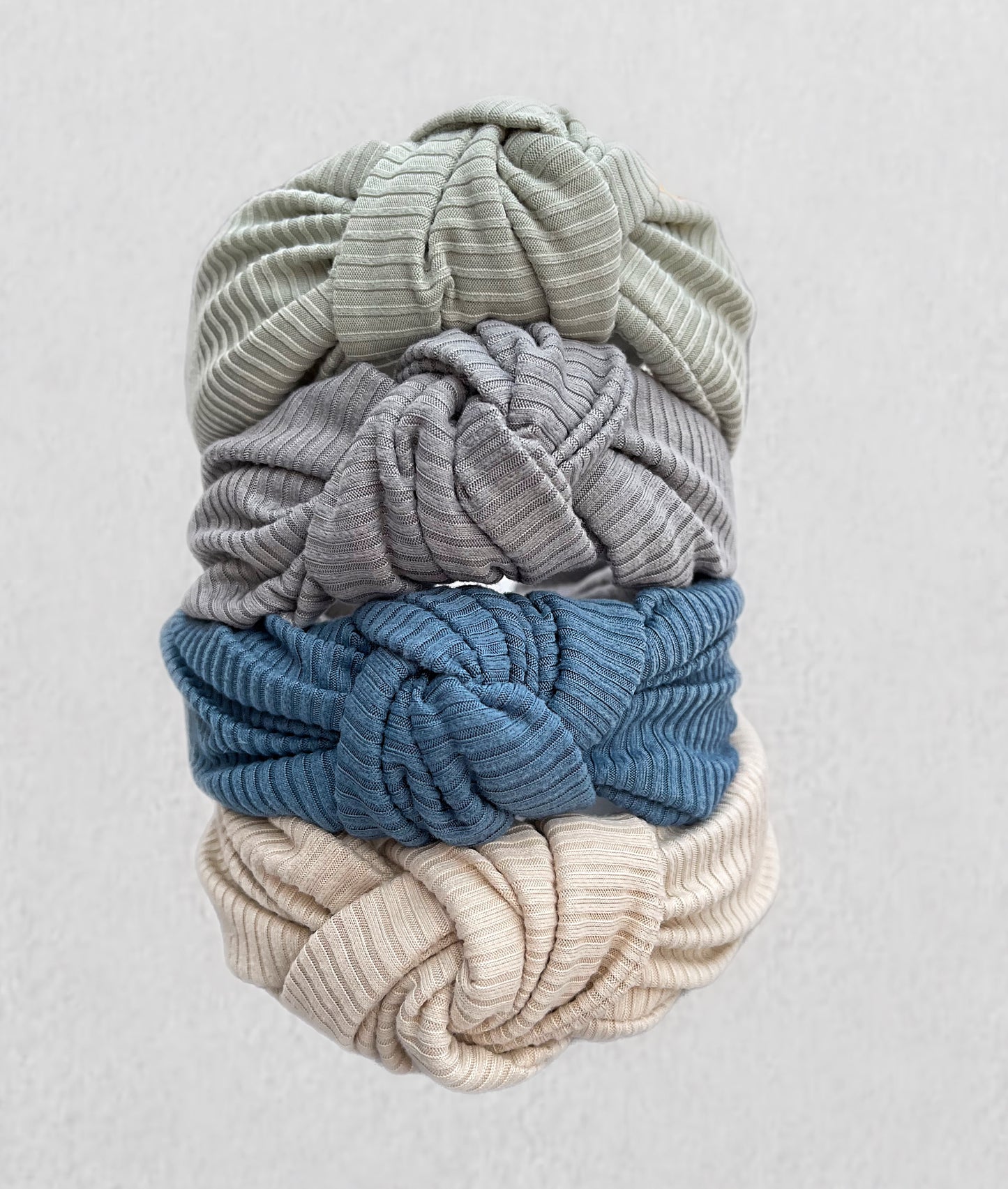 Ribbed, top knot hard headbands in varying colors- cream, sage green, blue, and gray.