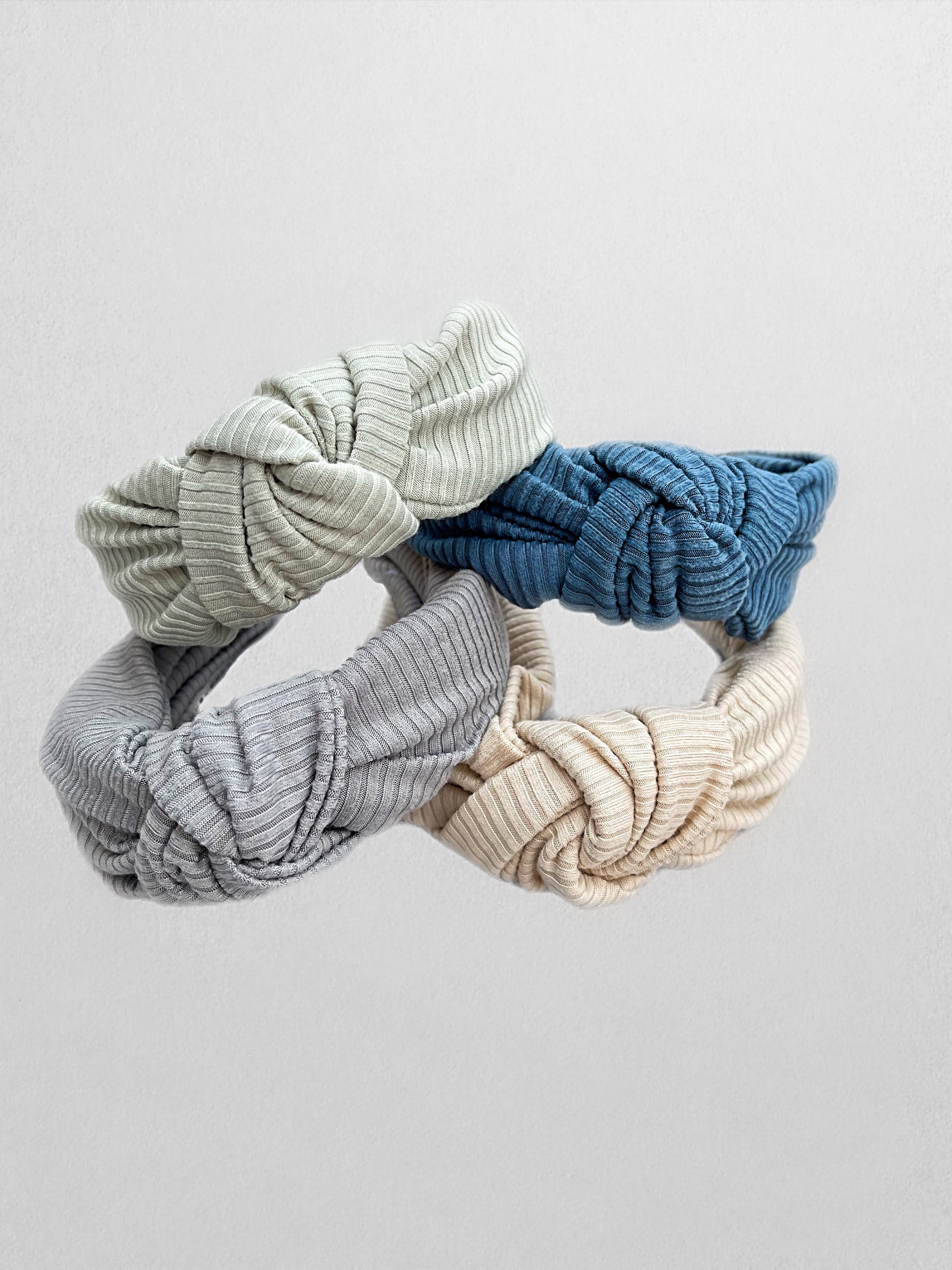 Ribbed, top knot hard headbands in varying colors- cream, sage green, blue, and gray.