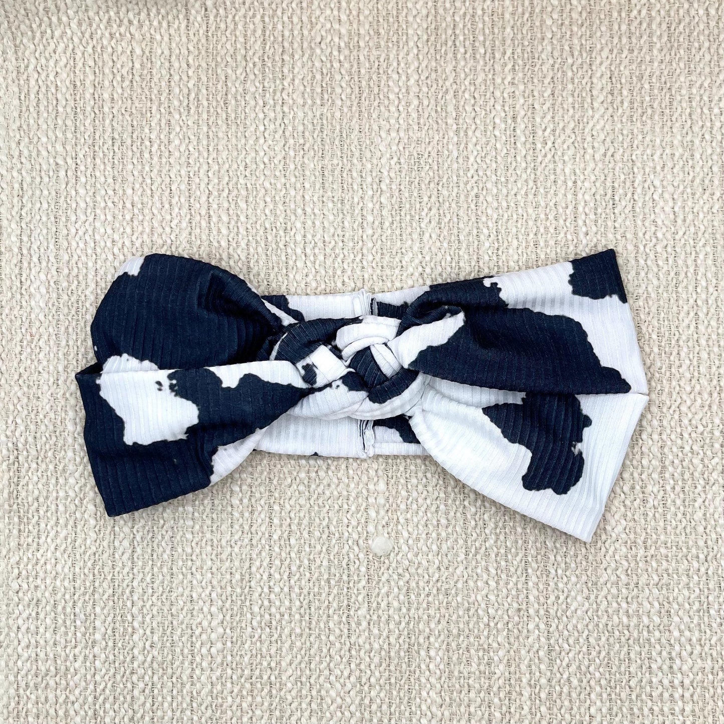 Black and white cow print headband in sailor knot style with ribbed fabric.