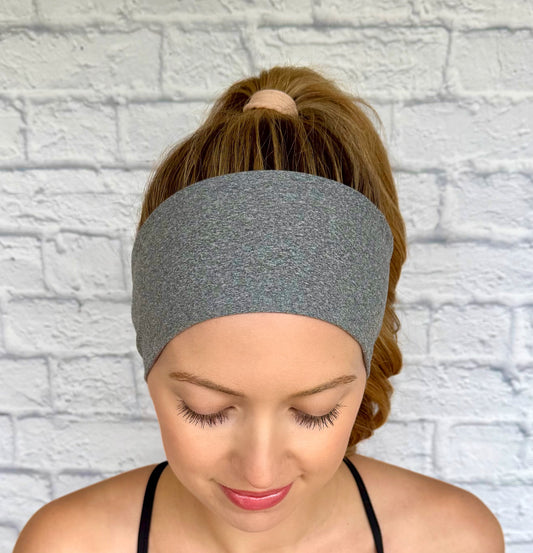 Woman with curled hair in ponytail wearing flat, stretchy, heather gray headband.