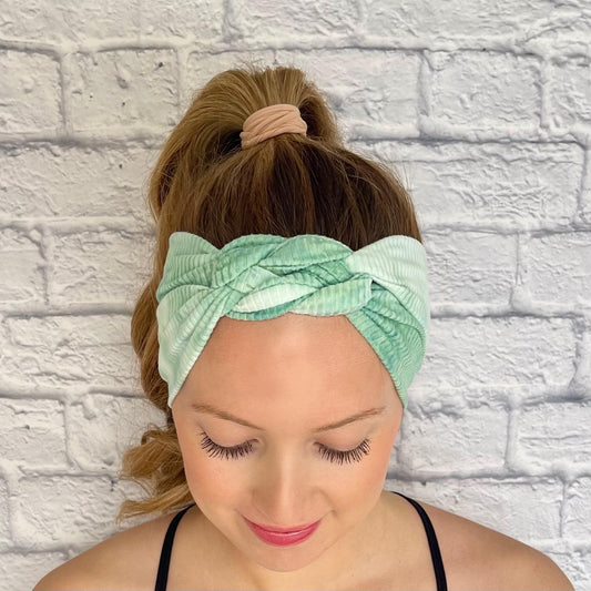 Woman with hair in curled ponytail wearing mint green, ribbed, tie dye sailor knot headband.