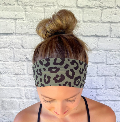 Woman with hair in bun wearing stretchy, green headband with black cheetah print.