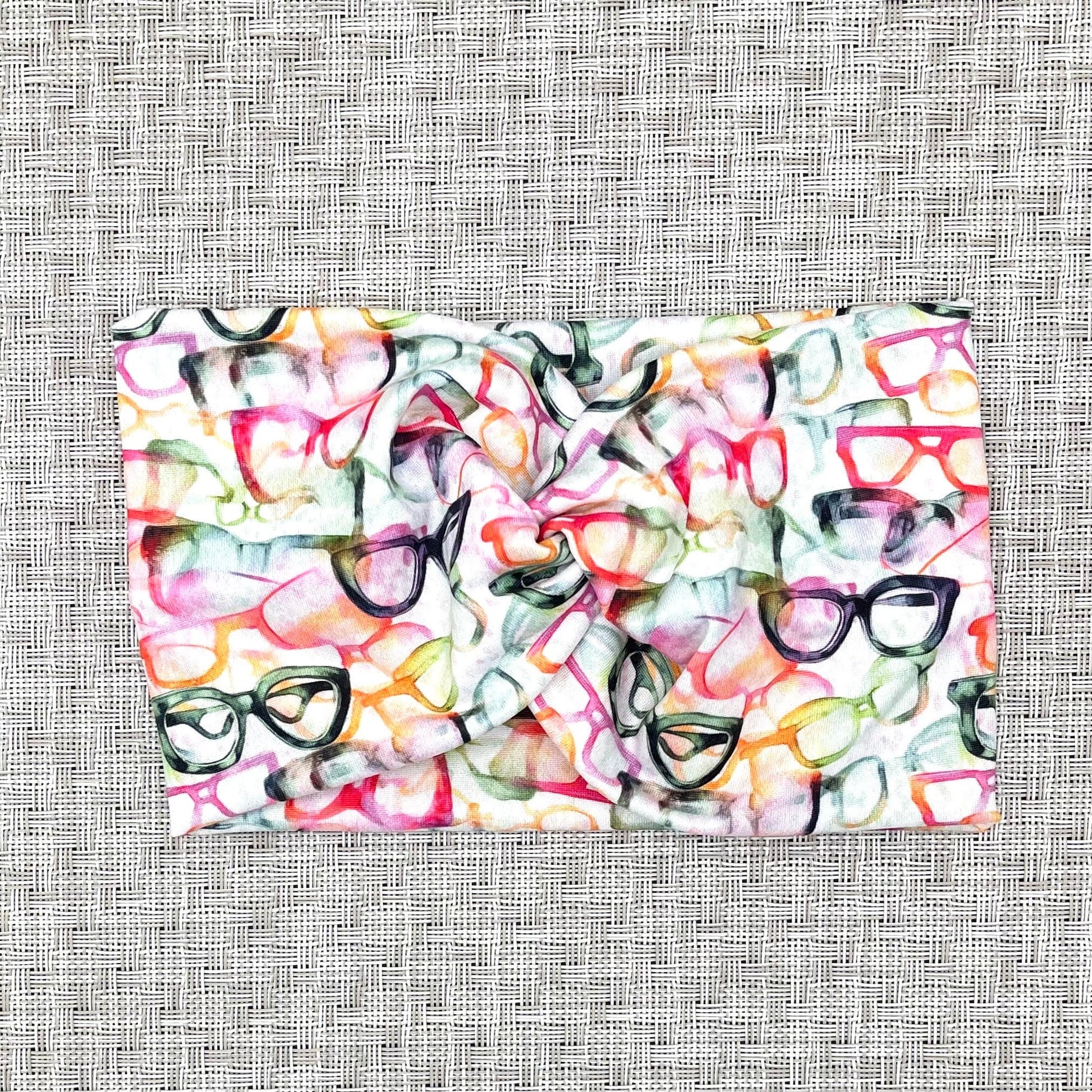 white, wide twist headband with glasses in rainbow colors