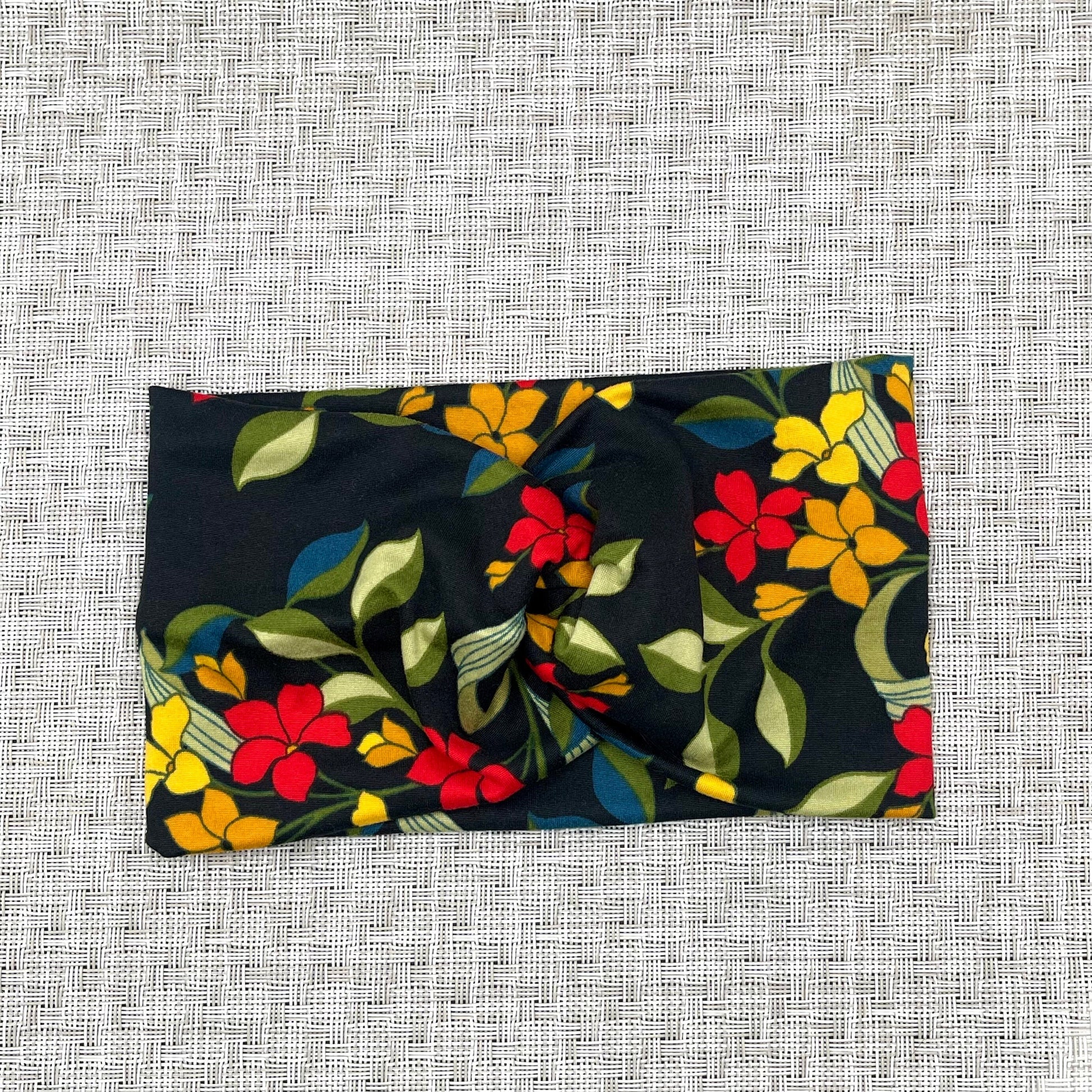 black headband with twist, floral print with red, yellow, and orange flowers