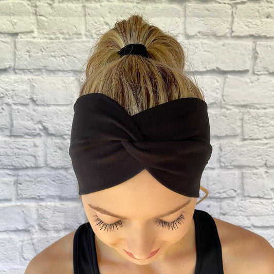 Woman wearing black, wide twisted stretchy headband.