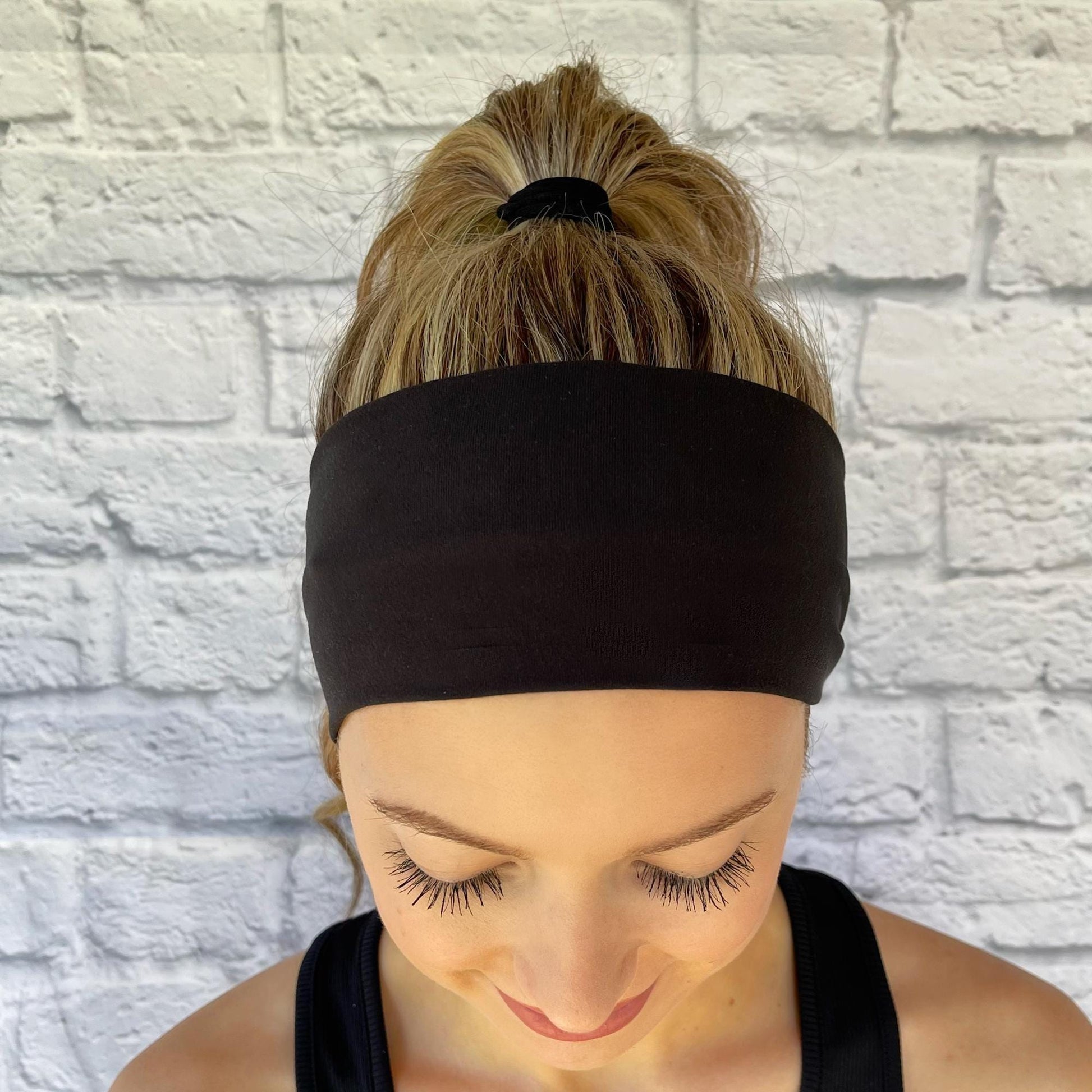 Woman with hair in ponytail wearing black headband.