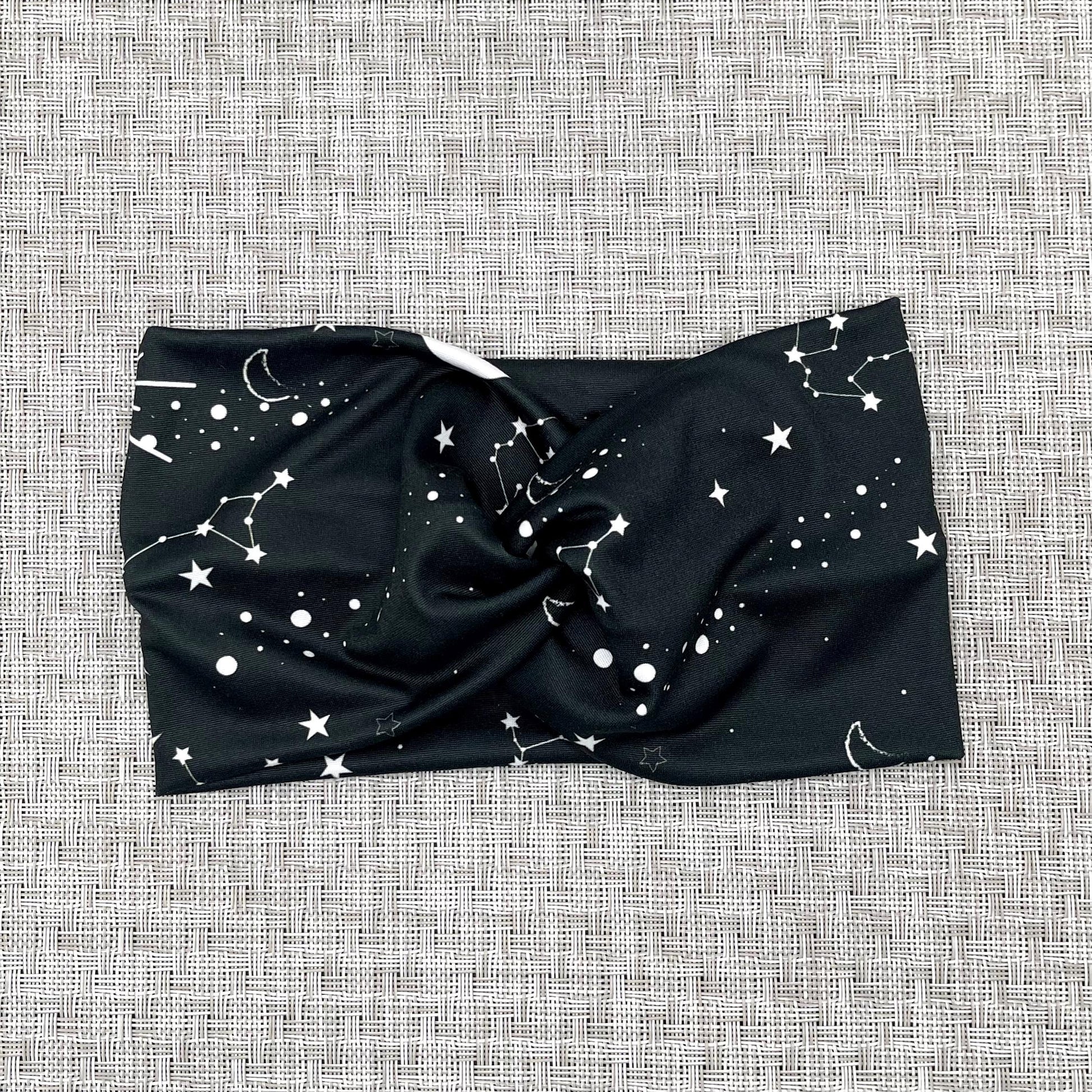 Wide, twisted headband in black with white galaxy theme print.