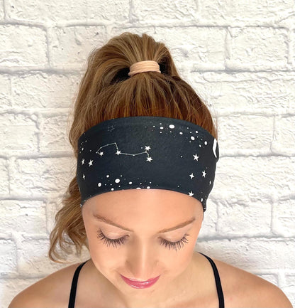 Woman with hair in ponytail wearing black headband with white space/galaxy theme print.