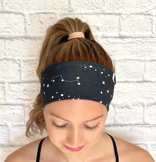 Woman with hair in ponytail wearing black headband with white space/galaxy theme print.