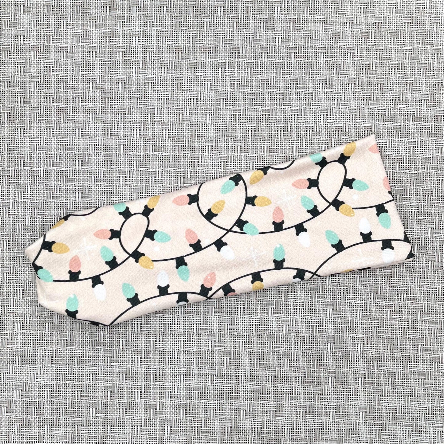 Flat, stretchy, light pink headband with Christmas light print.