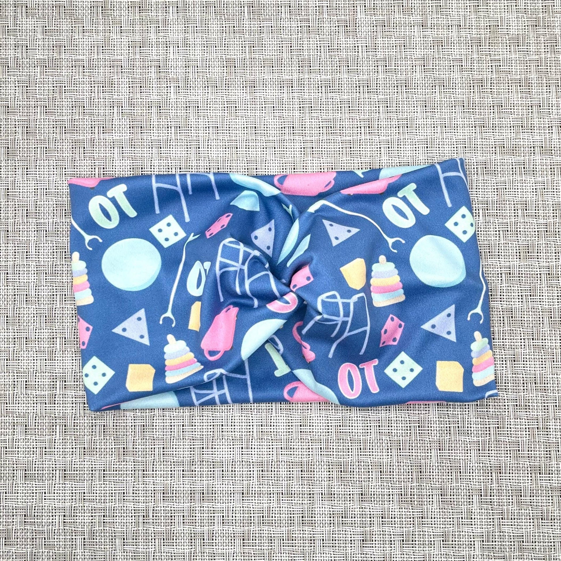 Wide, twisted, blue headband with "OT" print and occupational therapy accessories theme print.