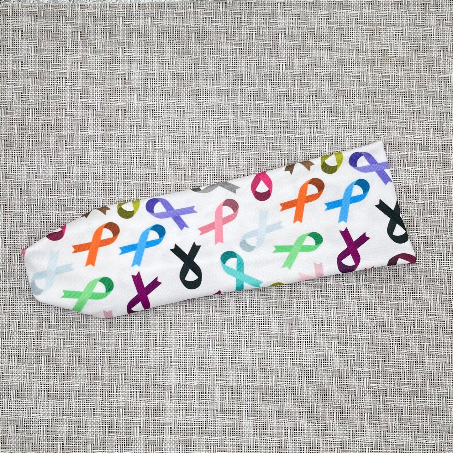 White, stretchy headband with ribbon print in varying color ribbons.