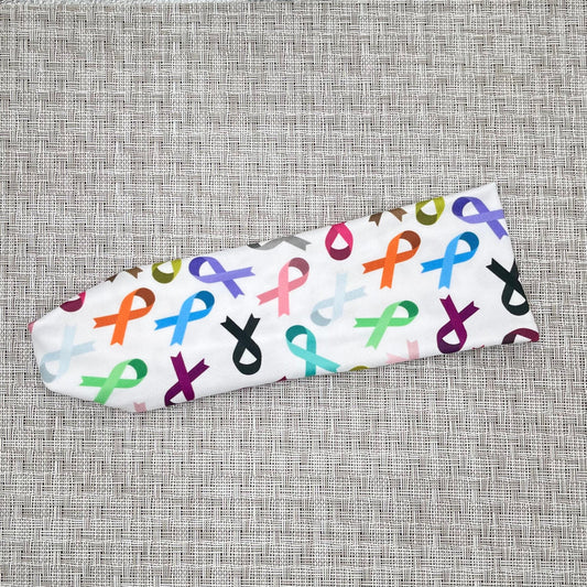 White, stretchy headband with ribbon print in varying color ribbons.