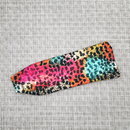 Flat, stretchy headband with rainbow cheetah print on a gray background.