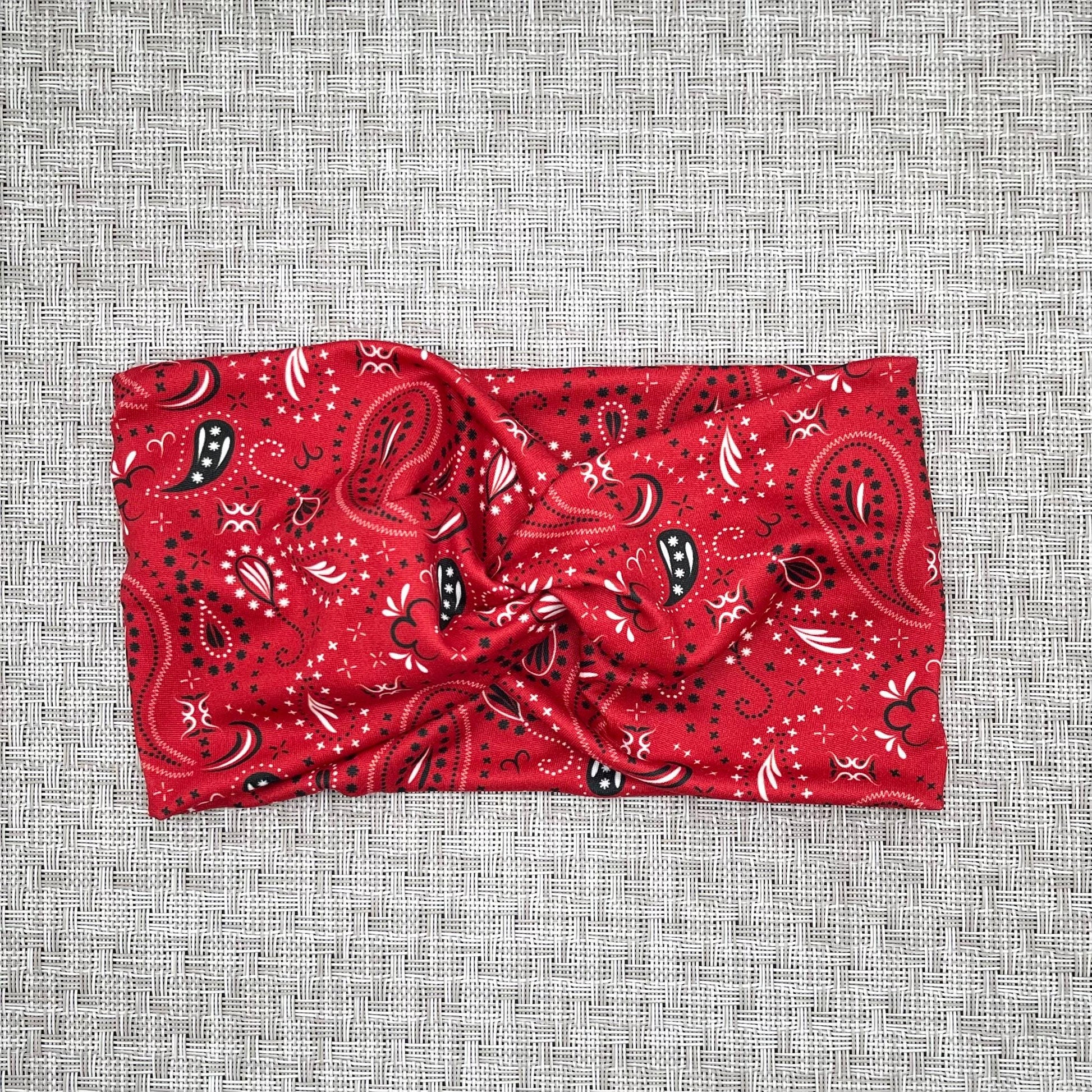 Wide, twisted headband with red bandana print on gray background.