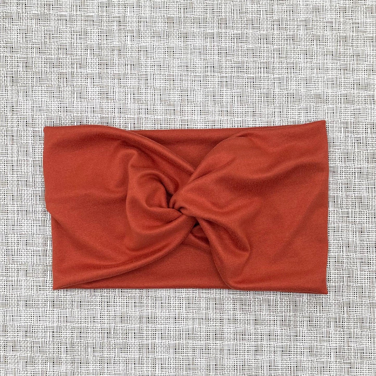 Wide, twisted headband in burnt orange color.