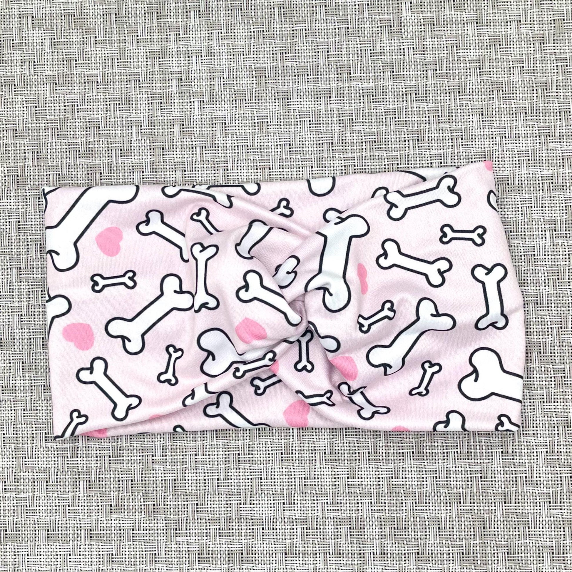 Wide, twisted headband in light pink with dog bone and heart print.