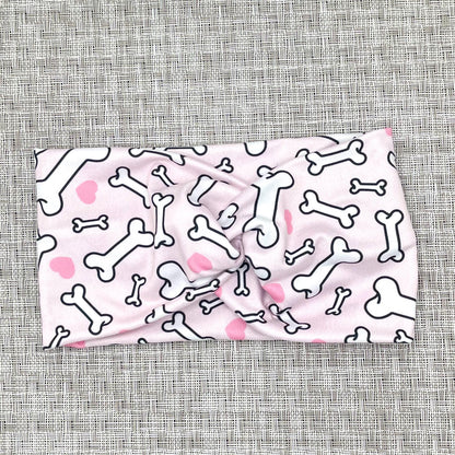 Wide, twisted headband in light pink with dog bone and heart print.
