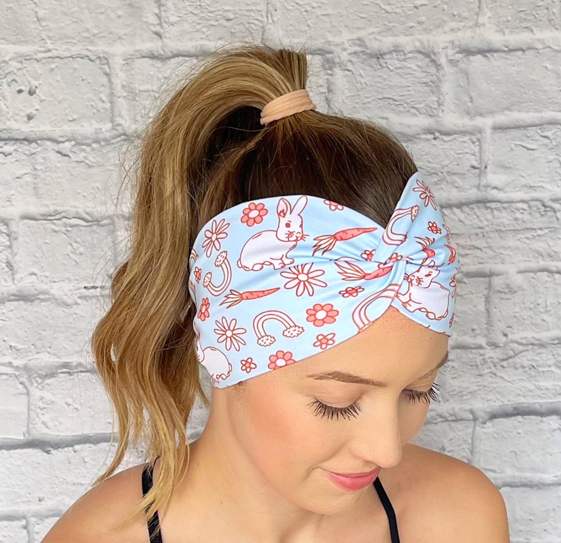 Woman with hair in curled ponytail wearing wide, twisted, light blue headband with Easter theme print.