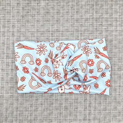 Wide, twisted, light blue headband with Easter theme print.