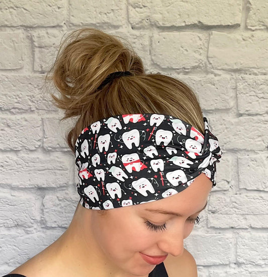 Woman with hair in bun wearing wide, twisted headband in black with white dental theme print.