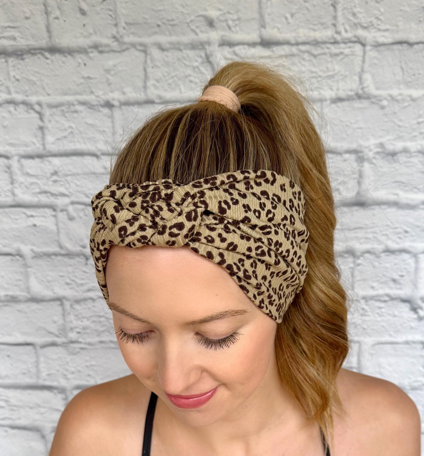 Woman with hair in ponytail wearing a sailor knot style headband with ribbed fabric in brown with black cheetah print.