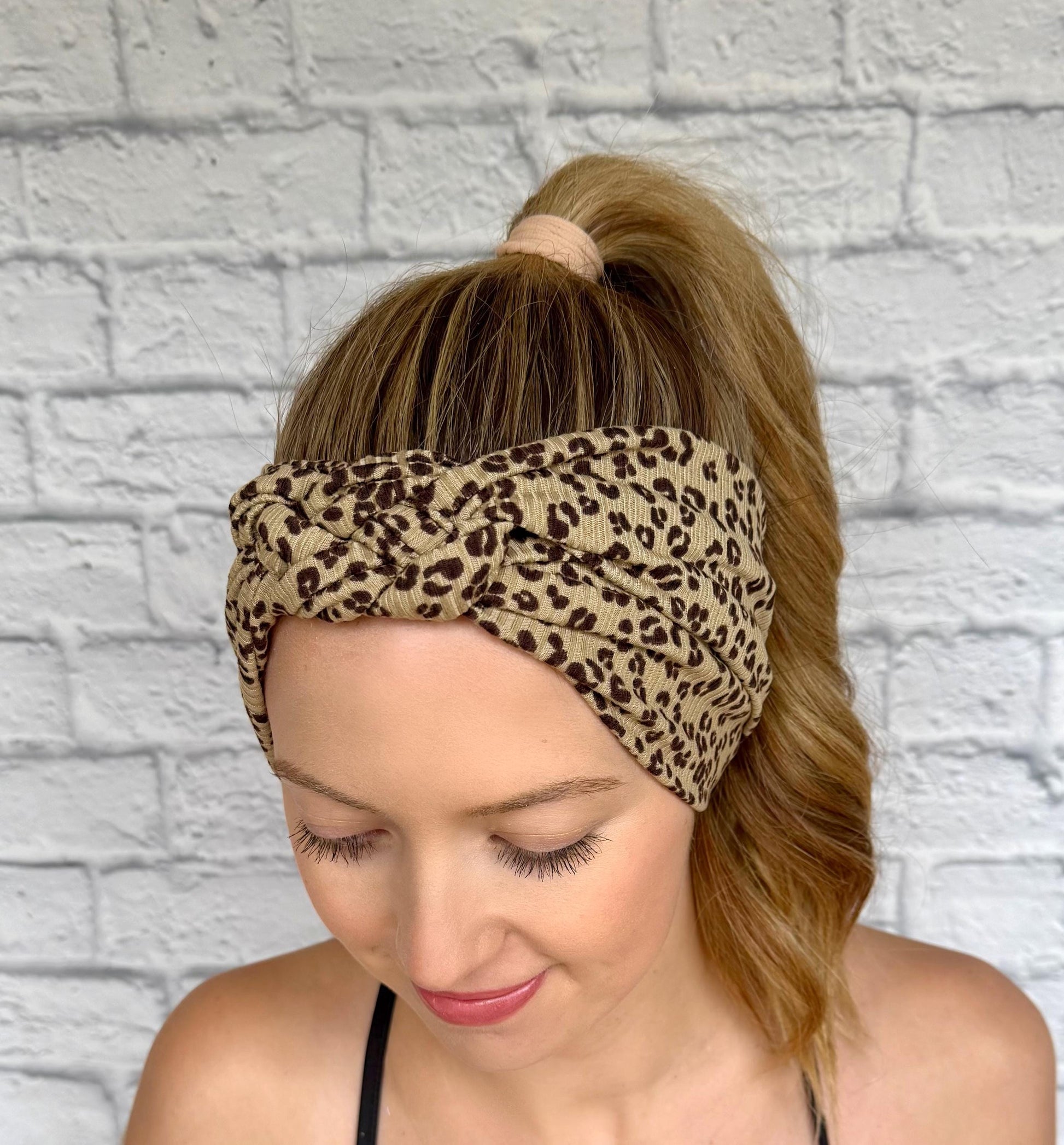 Woman with hair in ponytail wearing a sailor knot style headband with ribbed fabric in brown with black cheetah print.