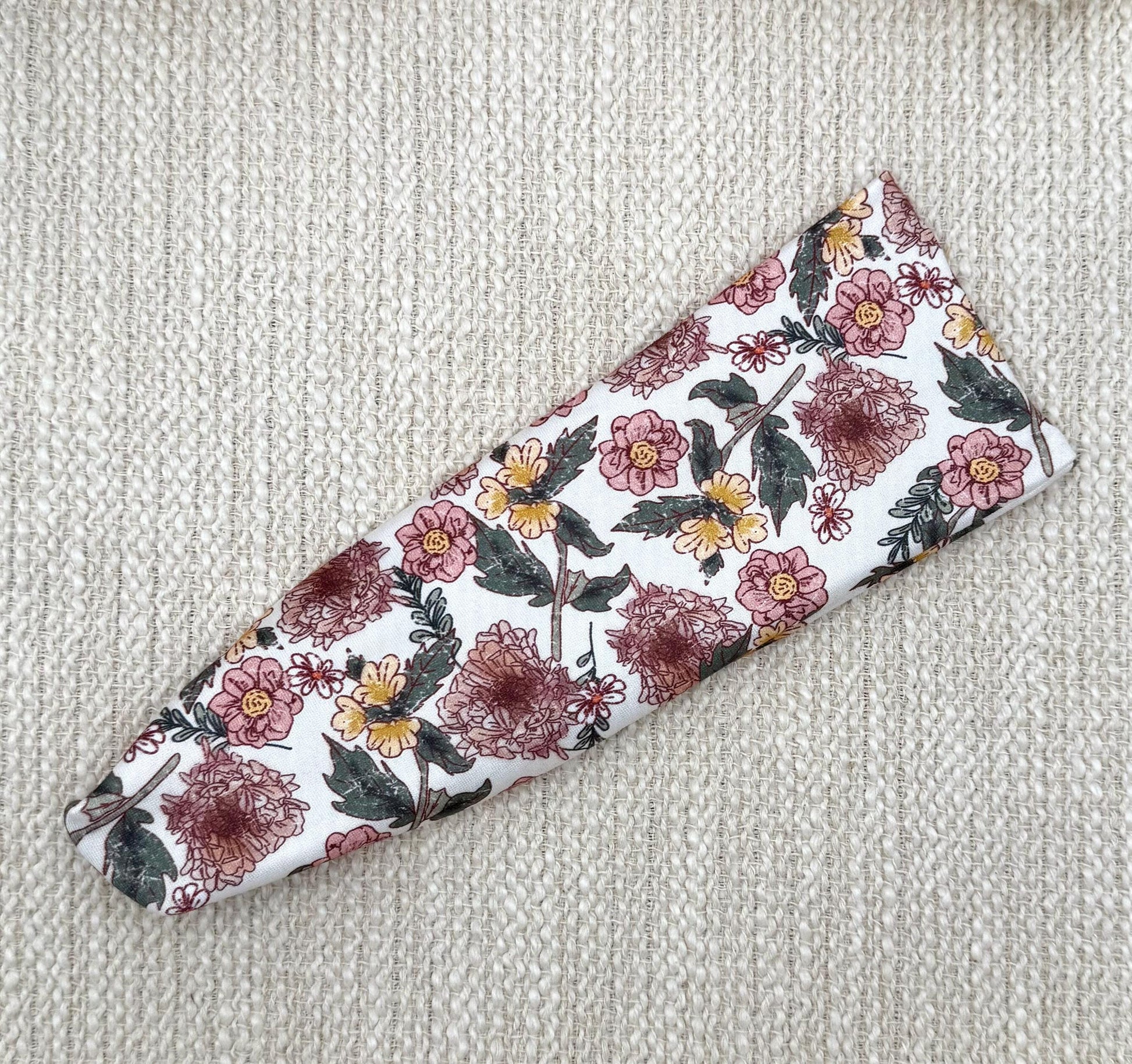 Flat, stretchy headband in white with pink and yellow flower print.