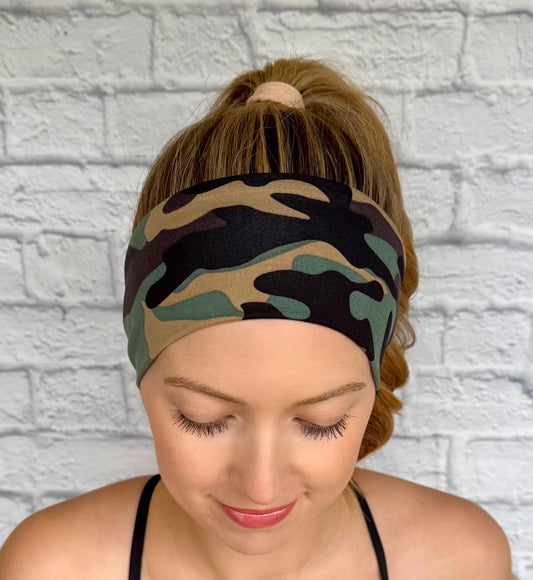 Woman with hair in curled ponytail wearing flat, stretchy headband in camo print.