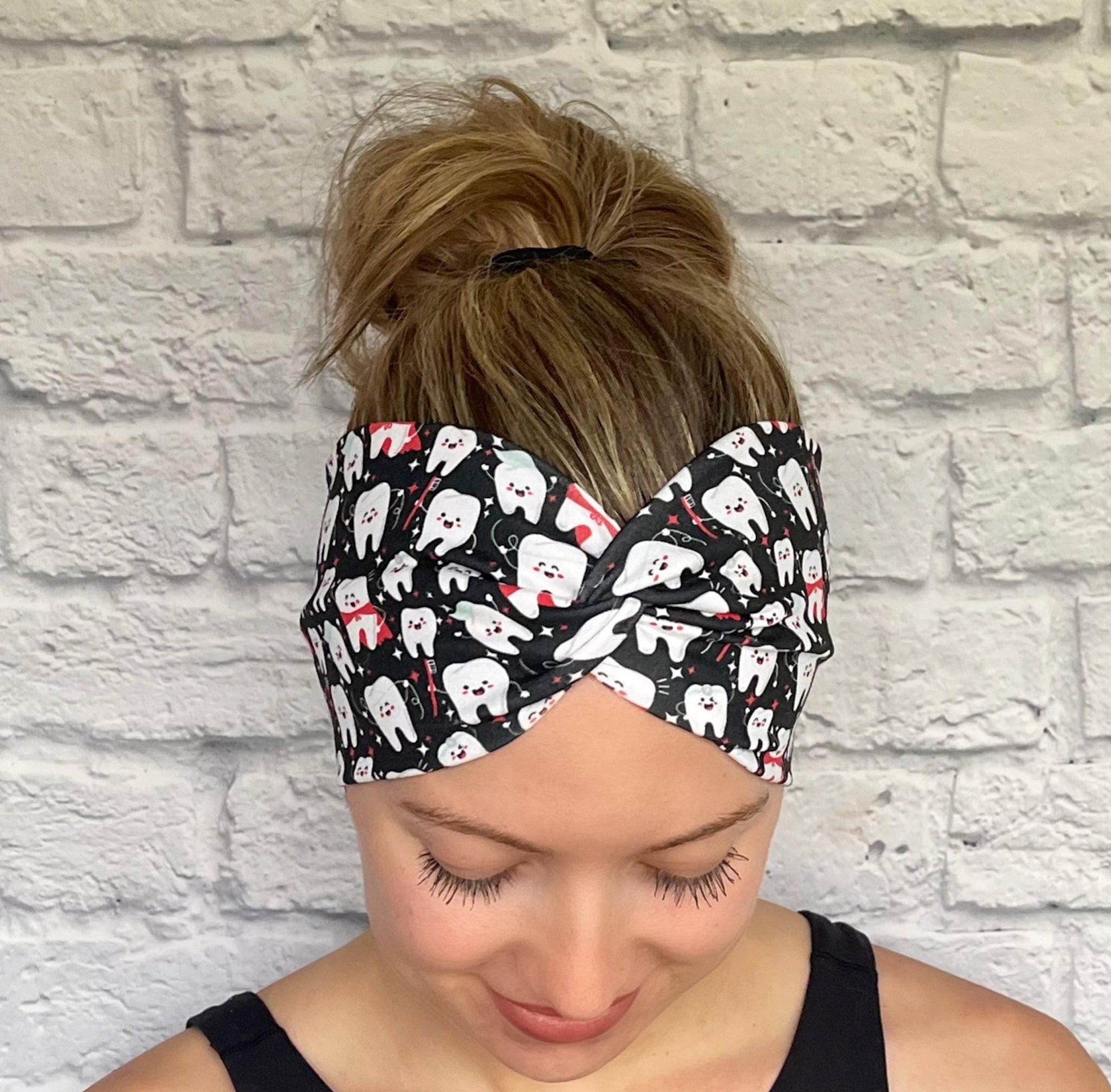 Woman with hair in bun wearing wide, twisted headband in black with white dental theme print.