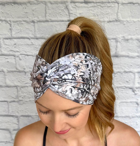 Woman with hair in ponytail wearing wide, twisted, stretchy headband in camo print.