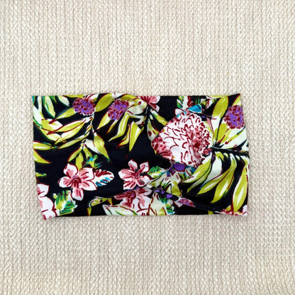 Wide, twisted headband in black with lime green, pink, white, and purple floral print.