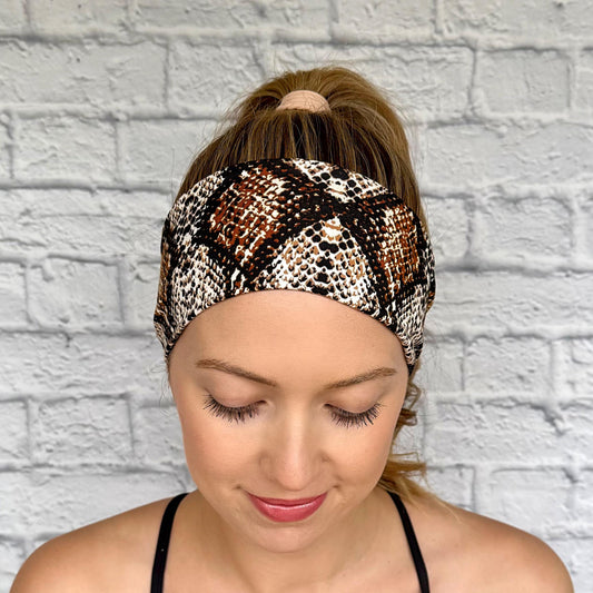 Woman with hair in ponytail wearing flat, stretchy headband with brown snakeskin print.