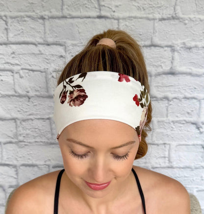 Woman with hair in ponytail wearing flat, stretchy headband in white with maroon rose print.