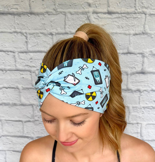 Woman with hair in ponytail wearing wide, twisted, blue headband with radiology theme print.