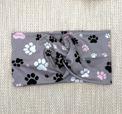 Wide, twisted, gray headband with pink, black, and white dog paw print.