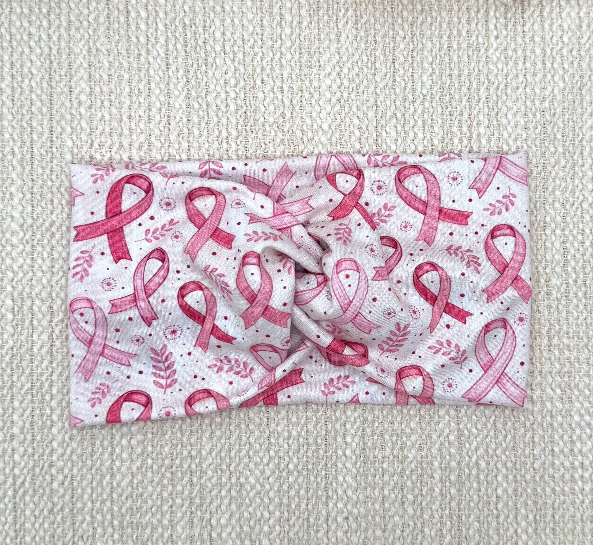 Wide, twisted, white/cream headband with pink ribbon and pink floral print.
